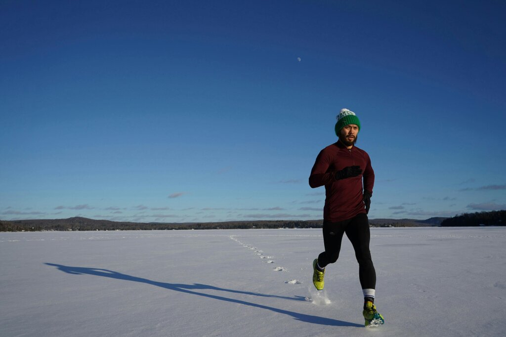 man running across snow in INDX sports and leisure clothing.